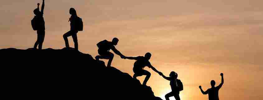 Silhouette,Of,People,Helping,Each,Other,Hike,Up,A,Mountain